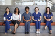 Female healthcare workers sitting in a hospital, full length