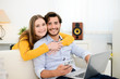 © W PRODUCTION - cheerful young couple on sofa at home websurfing and shopping online with laptop computer internet technology