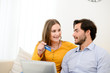 © W PRODUCTION - cheerful young couple on sofa at home websurfing and shopping online with credit card, a laptop computer and internet technology