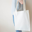 Blank white cotton tote bag with handle mock up design. Close up of woman holding eco or reusable shopping bag. No plastic bag and ecology concept.
