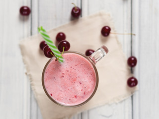 Wall Mural - Milkshake or cherry smoothie on white wooden table. Wholesome breakfast