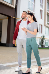 Wall Mural - woman using smartphone while walking with husband on street