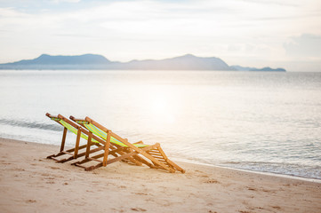 Bright color wooden beach chairs on island tropical beach