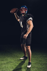 american football player on green grass throwing ball on black