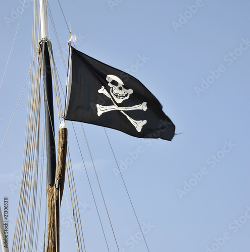 Fotografering The pirates flag, the jolly roger, waving on a blue sky background
