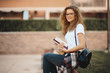 © chika_milan - Female student sitting in a campus and waiting for class to begin. Books in hands.