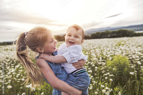 Fotografía Cute child girl at camomile field daisy with baby brother