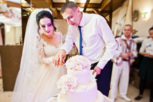 Wedding Couple Cutting Their Gorgeous White Wedding Cake In The Restaurant.