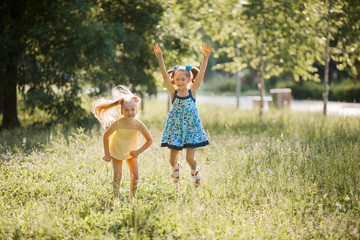 Wall Mural - two beautiful young joyful jumping girls in the summer in the park