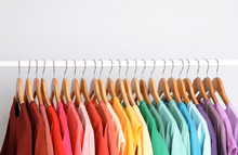 Rack With Rainbow Clothes On Light Background