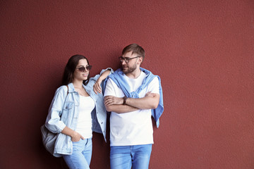 Wall Mural - Young hipster couple in stylish jeans posing near color wall
