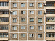 The texture of the wall of the apartment building with old windows and balconies on the sides. Abstract background of old paneled high-rise building.