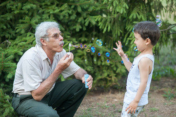 grandfather with grandson blowing soap bubbles