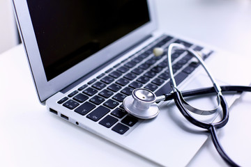 Wall Mural - Stethoscope lying on a laptop keyboard in a concept of online medicine or troubleshooting the computer viewed low angle with copy space