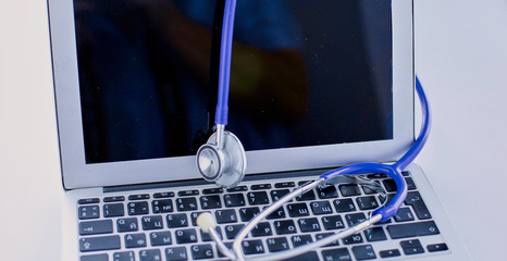 Wall Mural - Stethoscope lying on a laptop keyboard in a concept of online medicine or troubleshooting the computer viewed low angle with copy space