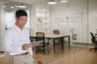 © mavoimages - Young Asian businessman using a tablet in an office