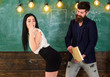 Man with beard slapping sexy student, chalkboard on background. Girl on guilty and helpless face punished by teacher. Schoolmaster punishes sexy student with slapping on her buttocks. Sex game concept