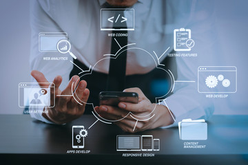 close up of businessman working with smart phone on wooden desk in modern office