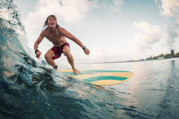 Wall Mural - Young surfer rides ocean tropical wave