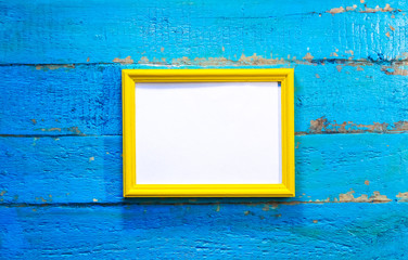 frame for photographs and images of yellow color with a blank white background inside on a blue textured wooden wall