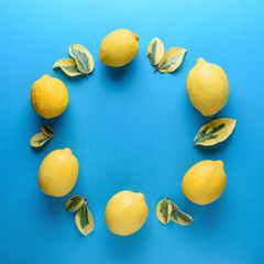 Creative summer pattern made of lemons and green leaves on blue background. Fruit minimal concept.