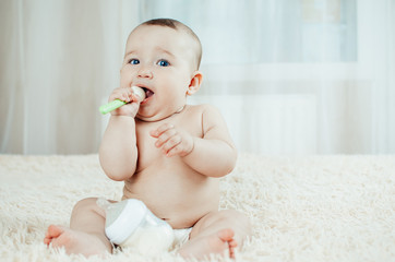 baby chest sitting with a rubber spoon in her hands playing with it