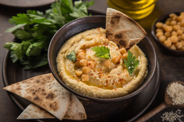 healthy homemade chickpea hummus with olive oil and smoked paprika, wooden background, top view