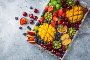Wall Mural - delicious fruits and berries platter.  Mango, kiwi, strawberry, grape, cherry, blueberry, peach and passion fruit