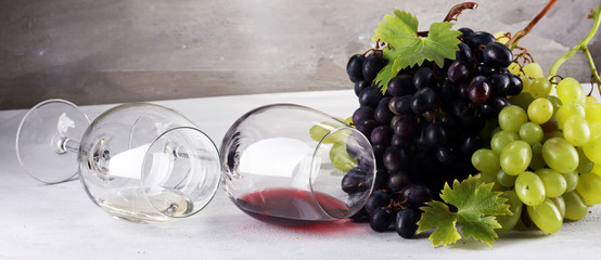 Red Wine and white wine with grapes and glasses on rustic background.