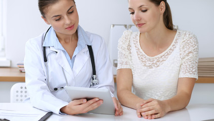 Doctor and patient having a pleasure talk while sitting at the desk at hospital office. Healthcare and medicine concept