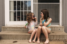 Sisters Holding Popsicles While Sitting On Steps 