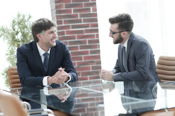 Two businessmen discussing tasks sitting at office table.