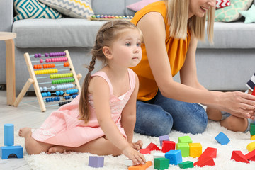 Poster - Young woman and cute girl playing with constructor on floor at home