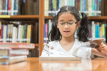 School education and literacy concept with Asian girl kid student learning and reading book in library or classroom