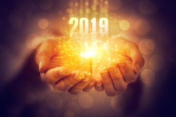 Wall Mural - new year 2019. magic energy emanating from women's hands. dark background with bokeh and a flash of 