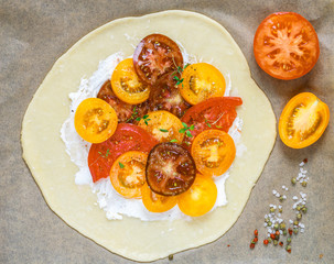 Preparation of summer Pai with cottage cheese, multi-colored (red, pink, orange, yellow, black) tomatoes and thyme. Delicious Galette