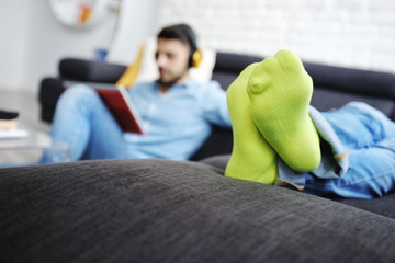 Wall Mural - Couple Lying On Sofa With Tablet PC and Earphones