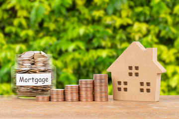 Model house, coin stack, and money jar on white background mortgage saving concept