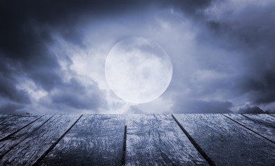 Wall Mural - Halloween background. Spooky sky with full moon and wooden table