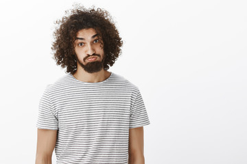 Wall Mural - Portrait of plyaful carefree attractive male model with beard and curly hair, sticking out tongue and pouting, making funny faces while hanging out on beach with friends, standing over gray background