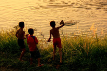 Local Kids Throuwing Rocks In Nam Song River At Sunset, Vang Vieng, Laos