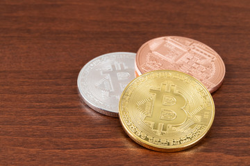 Gold silver and bronze bitcoin token on wooden background