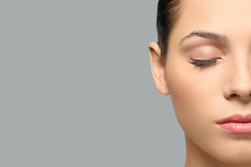 young woman with natural eyebrows on grey background