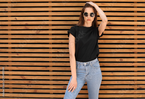 Fotografía Young woman wearing black t-shirt against wooden wall on street