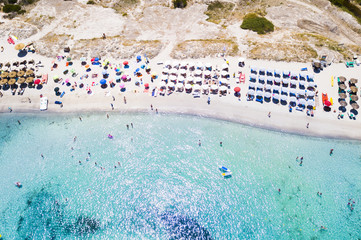 Wall Mural - Aerial view of an emerald and transparent Mediterranean sea with a white beach full of beach umbrellas and tourists who relax and take a bath. Costa Smeralda, Sardinia, Italy.