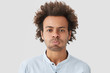 © wayhome.studio  - Sullen mixed race male pouts lips and blows cheeks, has discontent expression, being dissatisfied with something, looks gloomy after quarrel with girlfriend, stands against white background.