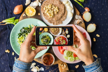 Smartphone food photography of vegetarian lunch or dinner. Woman hands taking phone photo of food in trendy style for social media or blogging.