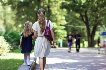 Rear view of young mother walking with little girl daughter in