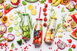 Summer clean and healthy lifestyle and fitness background with various infused water in bottles, colorful sliced ingredients: fruits, berries, vegetables, herbs on white  background, top view
