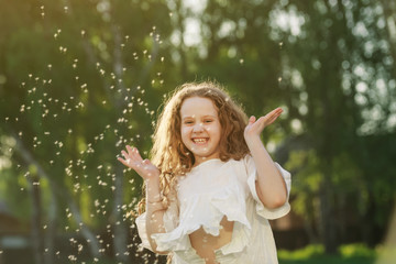 Wall Mural - Cute curly baby with flying dandelion seed outdoors.